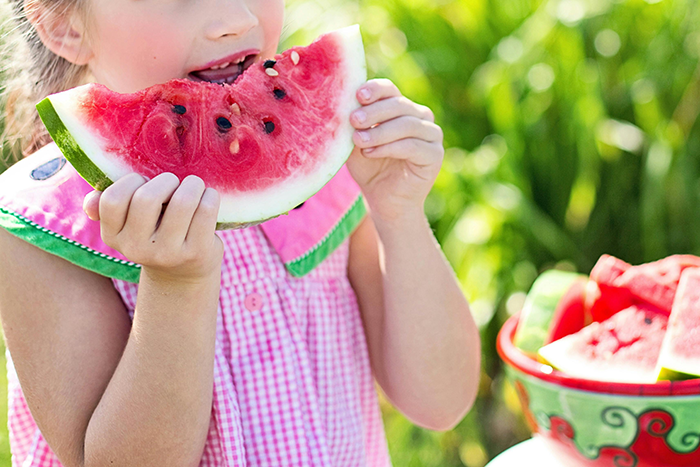 Child enjoying a slice of watermelon outdoors, illustrating food preferences and dietary habits. Child enjoying a slice of watermelon outdoors, illustrating food preferences and dietary habits.
