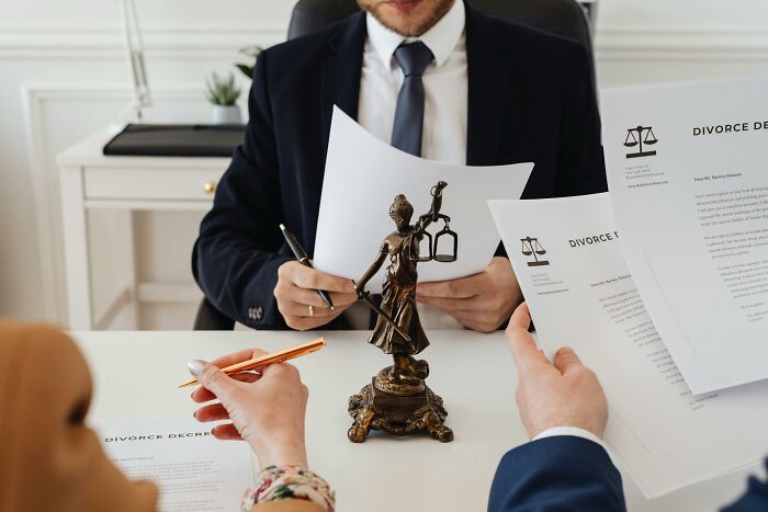 People reviewing divorce documents at a lawyer's office, representing occupations with a statue of Lady Justice on the table.