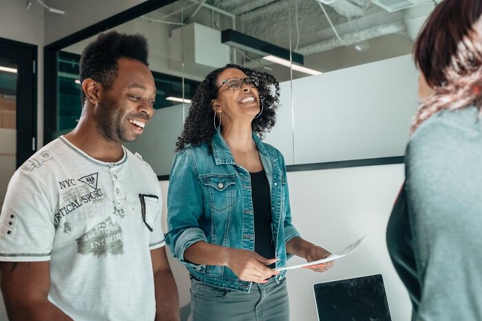 Two people smiling in a bright office, embodying the traits of truly good people with their positive interaction.