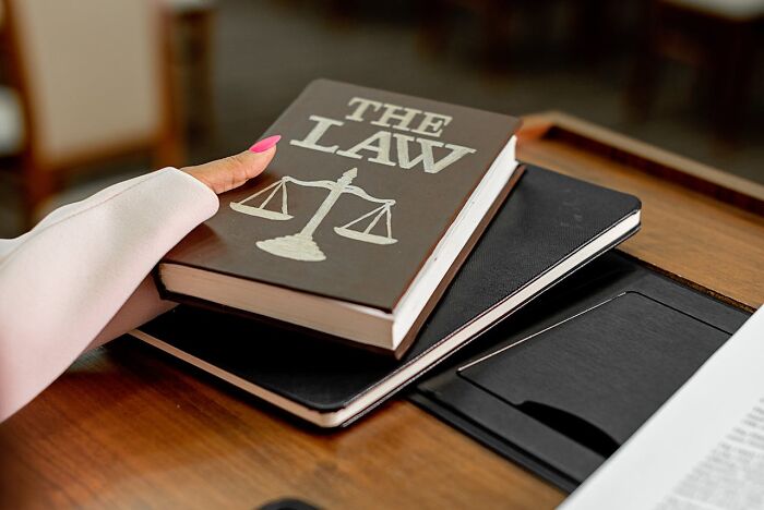A hand holding a law book with scales of justice, symbolizing principles of a truly good person.