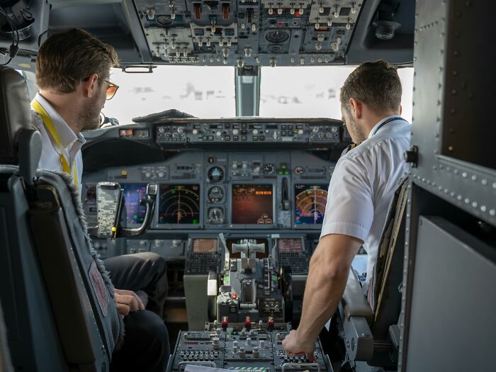 Pilots in a cockpit operating controls.