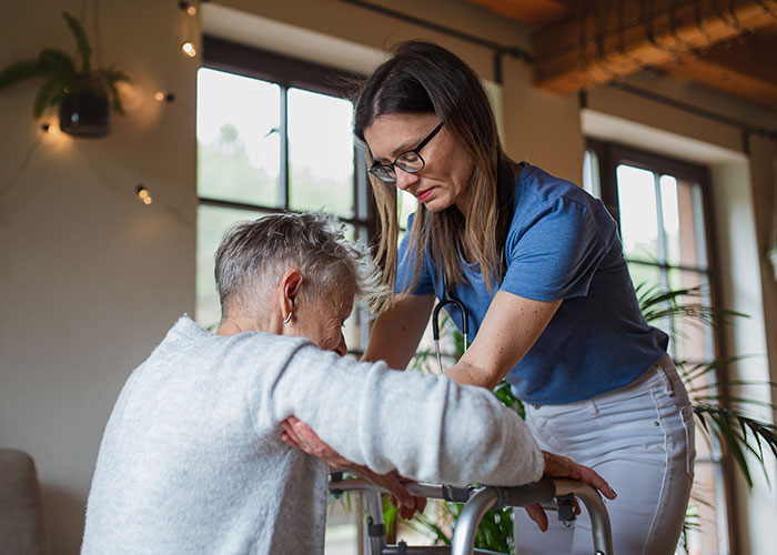 Woman assisting elderly mother with a walker in care facility, highlighting family dynamics over caregiving decisions. Woman assisting elderly mother with a walker in care facility, highlighting family dynamics over caregiving decisions.