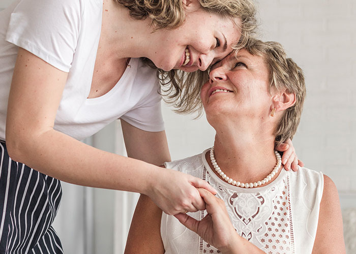 Mother and daughter share a warm moment, smiling and holding hands in a caring environment. Mother and daughter share a warm moment, smiling and holding hands in a caring environment.