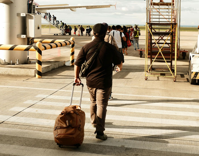 Man with suitcase walking on airport tarmac, boarding a plane, ignoring the child’s tantrum situation on flight. Man with suitcase walking on airport tarmac, boarding a plane, ignoring the child’s tantrum situation on flight.