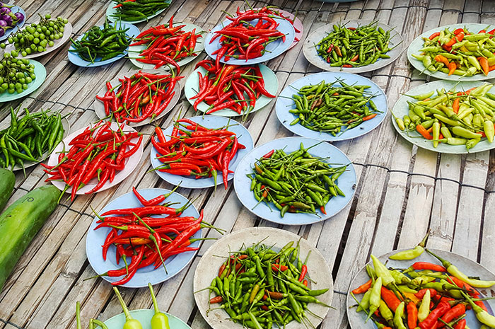 Assorted chili peppers arranged on plates over a bamboo surface, showcasing a vibrant and spicy collection. Assorted chili peppers arranged on plates over a bamboo surface, showcasing a vibrant and spicy collection.