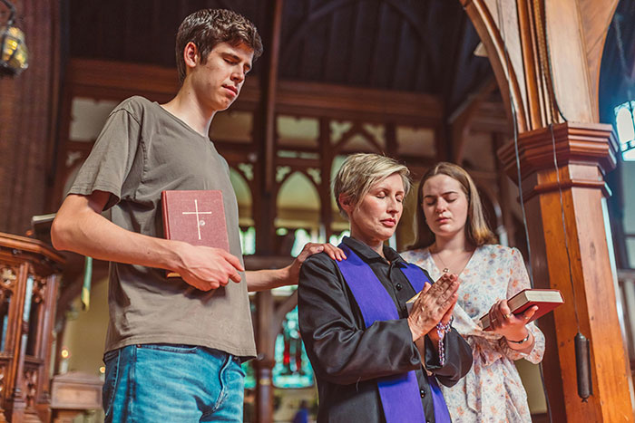A woman in church with two others, holding a Bible and rosary, symbolizing Christian faith and devotion. A woman in church with two others, holding a Bible and rosary, symbolizing Christian faith and devotion.