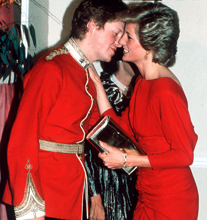 A man in a red uniform interacts closely with a woman in a red dress at a formal event. A man in a red uniform interacts closely with a woman in a red dress at a formal event.