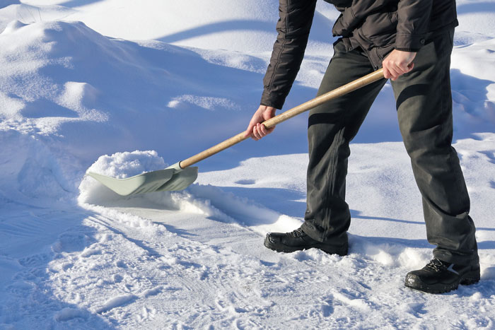 Person shoveling snow from a driveway. Person shoveling snow from a driveway.