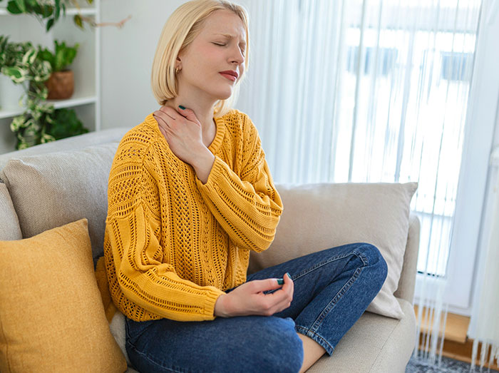 Woman in yellow sweater sitting on couch, looking stressed, related to an office Christmas party situation. Woman in yellow sweater sitting on couch, looking stressed, related to an office Christmas party situation.