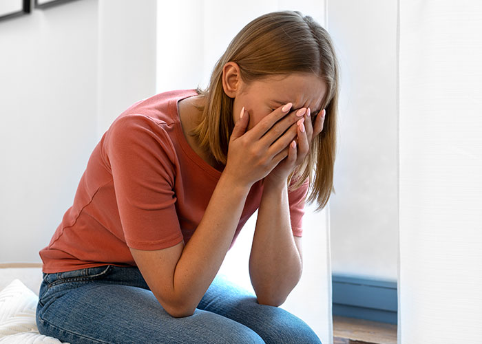 Person sitting with hands covering face, appearing upset or stressed, possibly regarding a Thanksgiving dish concern. Person sitting with hands covering face, appearing upset or stressed, possibly regarding a Thanksgiving dish concern.