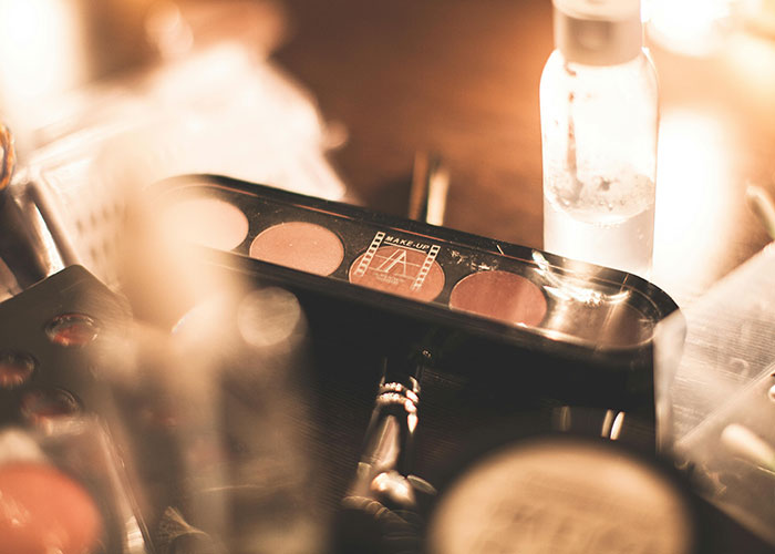 Makeup palette and skincare bottle on a table, highlighting shared beauty products. Makeup palette and skincare bottle on a table, highlighting shared beauty products.