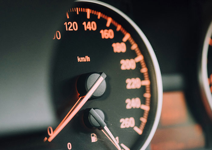 Close-up of a car speedometer glowing at night, highlighting driving experiences. Close-up of a car speedometer glowing at night, highlighting driving experiences.