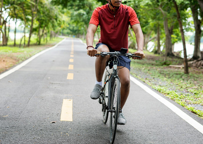 Person cycling on a tree-lined road, highlighting unique experiences seen while driving at night. Person cycling on a tree-lined road, highlighting unique experiences seen while driving at night.