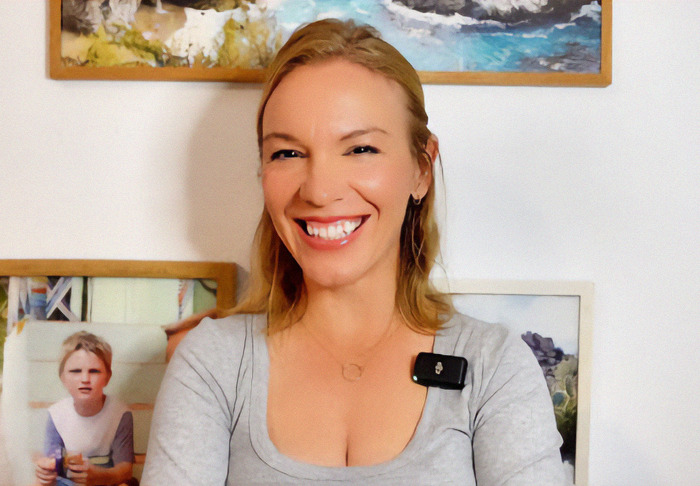 Ex-Scientologist Jenna Miscavige smiling, discussing alleged brainwashing and song in an interview setting, framed photos in the background. Ex-Scientologist Jenna Miscavige smiling, discussing alleged brainwashing and song in an interview setting, framed photos in the background.