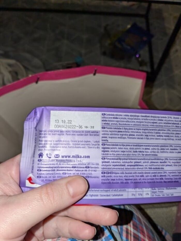 Expired chocolate bar held by a hand, showing past expiration date, possibly a Secret Santa gift. Expired chocolate bar held by a hand, showing past expiration date, possibly a Secret Santa gift.