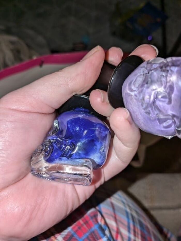 Hand holding expired Secret Santa gift, featuring blue and purple nail polish bottles. Hand holding expired Secret Santa gift, featuring blue and purple nail polish bottles.