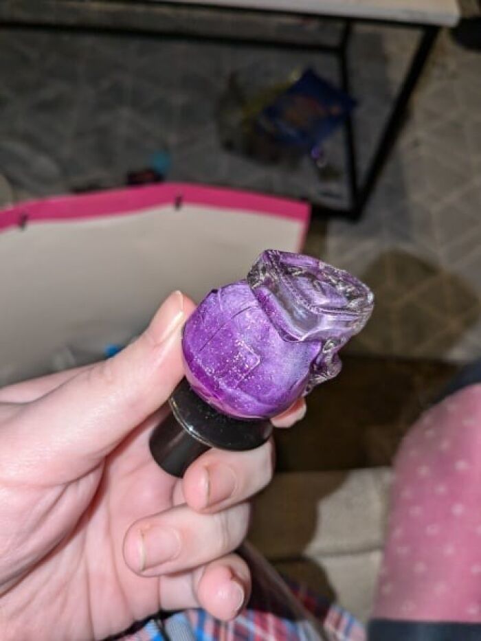 Hand holding a small purple nail polish bottle, associated with Secret Santa gift idea. Hand holding a small purple nail polish bottle, associated with Secret Santa gift idea.