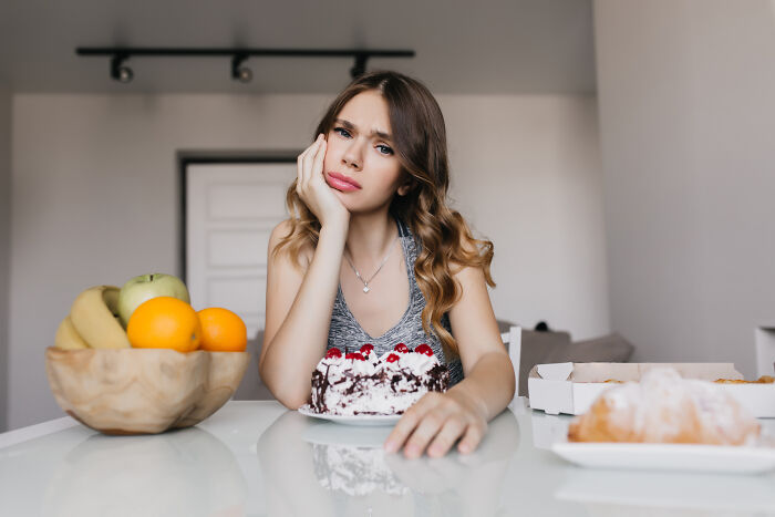 Woman in a kitchen, looking thoughtful, sitting by a cake, symbolizing single-mother-sister-Christmas themes. Woman in a kitchen, looking thoughtful, sitting by a cake, symbolizing single-mother-sister-Christmas themes.