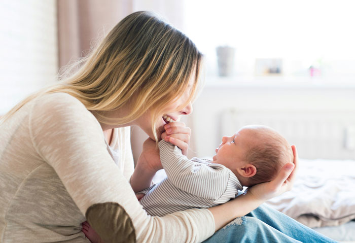 Woman using baby talk while holding infant, smiling warmly. Woman using baby talk while holding infant, smiling warmly.