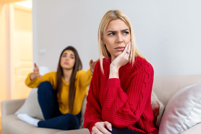 Two women sitting on a couch, one frustrated, the other using baby talk. Two women sitting on a couch, one frustrated, the other using baby talk.