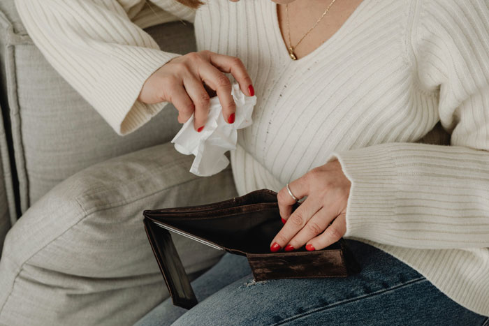 Person in white sweater holding an open empty wallet, symbolizing debt clearance effort using $5k. Person in white sweater holding an open empty wallet, symbolizing debt clearance effort using $5k.