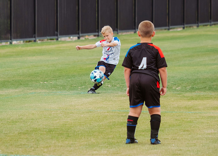 Children playing soccer on a field, one kicking the ball, related to police involvement for unusual reasons.