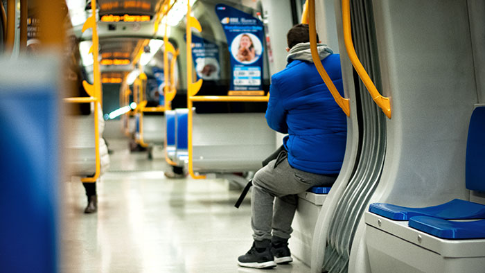 Man in blue jacket sitting alone on subway, facing away. Man in blue jacket sitting alone on subway, facing away.
