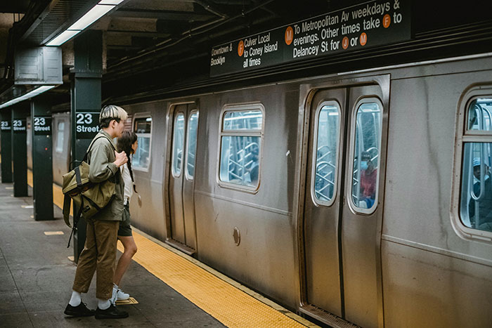 People standing on a subway platform by a train in a city setting. People standing on a subway platform by a train in a city setting.