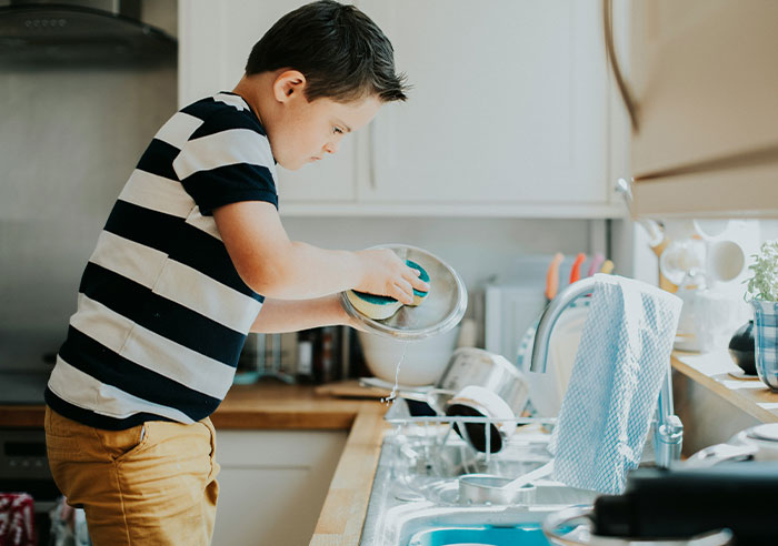 Child washing dishes in a kitchen, wearing a striped shirt, symbolizing family dynamics with 10 kids. Child washing dishes in a kitchen, wearing a striped shirt, symbolizing family dynamics with 10 kids.
