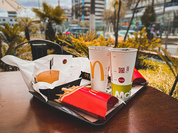 Fast food tray with burger, fries, and drinks outdoors, highlighting wheat allergy concerns. Fast food tray with burger, fries, and drinks outdoors, highlighting wheat allergy concerns.