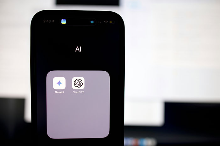 Smartphone displaying AI folder with ChatGPT and Gemini apps on screen. Smartphone displaying AI folder with ChatGPT and Gemini apps on screen.