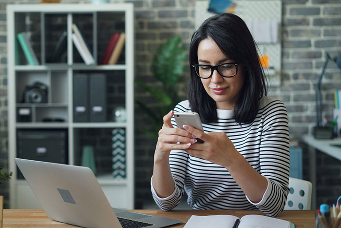 Tenant using ChatGPT on phone at desk with laptop, planning legal strategy against landlord. Tenant using ChatGPT on phone at desk with laptop, planning legal strategy against landlord.