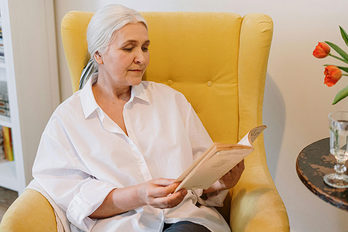 Elderly woman in a yellow chair, reading a menu, linked to a family Thanksgiving dinner story involving a hidden cake and backup pie. Elderly woman in a yellow chair, reading a menu, linked to a family Thanksgiving dinner story involving a hidden cake and backup pie.