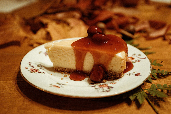 Slice of cheesecake on a floral plate with cherry topping, symbolizing a holiday family dessert. Slice of cheesecake on a floral plate with cherry topping, symbolizing a holiday family dessert.