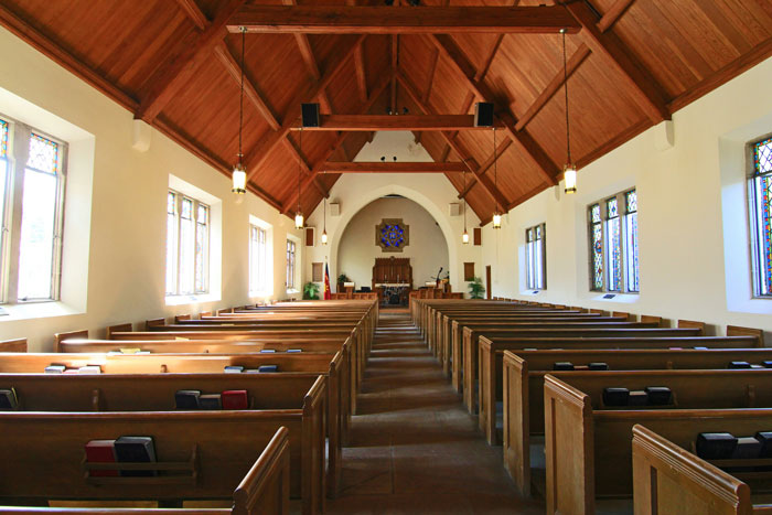 Inside view of an empty church highlighting wooden pews and stained glass windows. Inside view of an empty church highlighting wooden pews and stained glass windows.