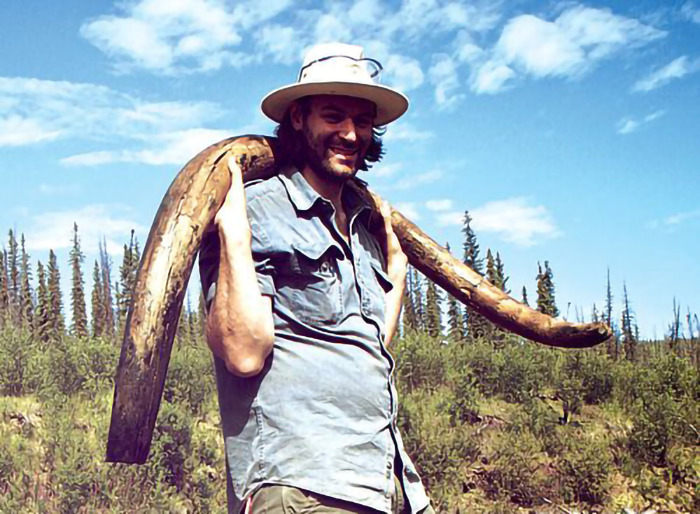 Man with woolly mammoth tusk in a forest setting. Man with woolly mammoth tusk in a forest setting.