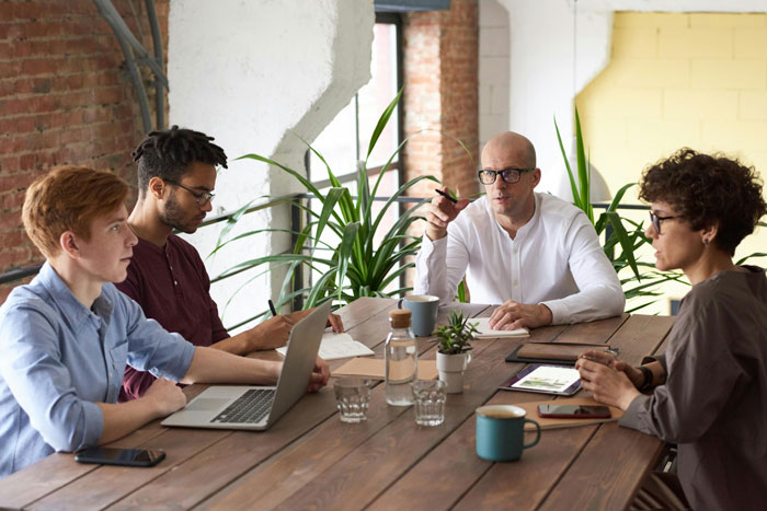 Office meeting with diverse employees around a wooden table, discussing workplace issues. Office meeting with diverse employees around a wooden table, discussing workplace issues.