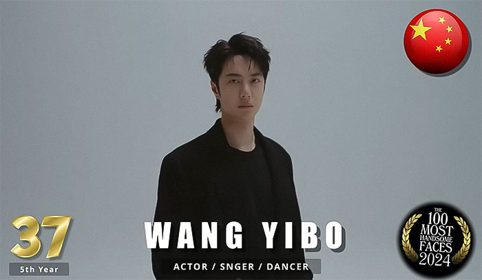 "Man in dark attire, part of 2024's most handsome men by critics, standing against a plain background with Chinese flag. "Man in dark attire, part of 2024's most handsome men by critics, standing against a plain background with Chinese flag.