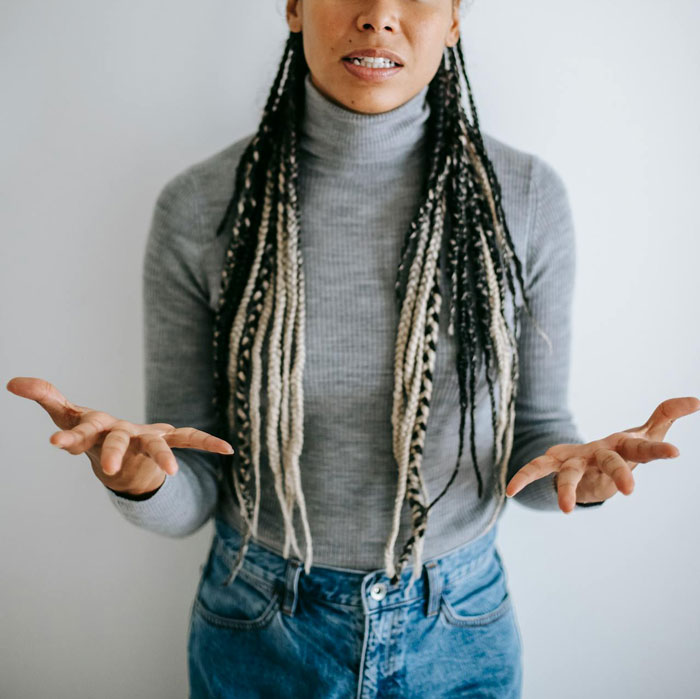 Woman gesturing emotionally in grey sweater and jeans, conveying tension. Woman gesturing emotionally in grey sweater and jeans, conveying tension.