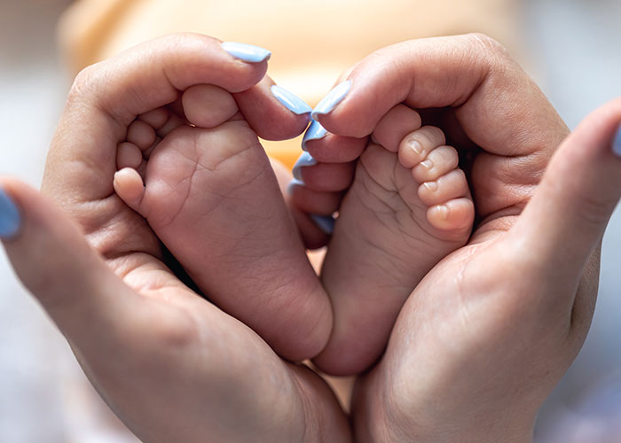 Mother holding baby's feet gently, emphasizing family bonds and protection. Mother holding baby's feet gently, emphasizing family bonds and protection.