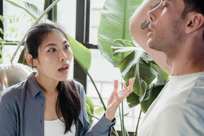 Woman expressing frustration to her partner in a room with plants, discussing his close relationship with his mother. Woman expressing frustration to her partner in a room with plants, discussing his close relationship with his mother.