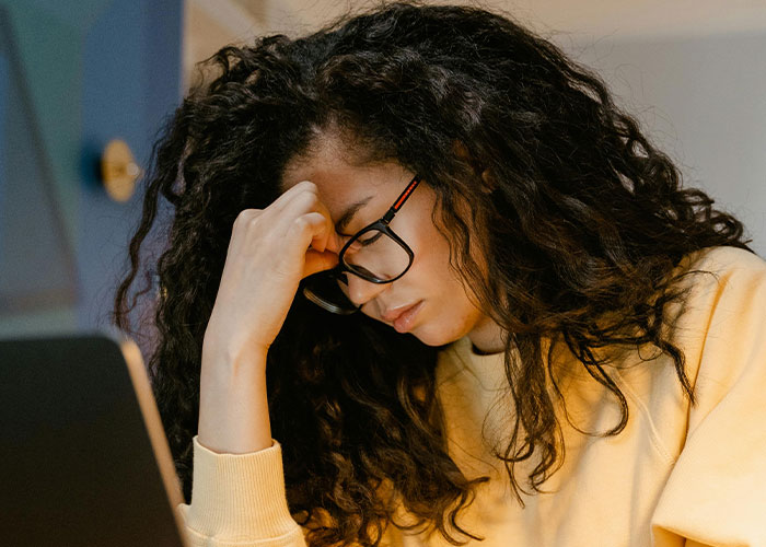 Woman in glasses sitting at a desk, looking upset over trust fund issues. Woman in glasses sitting at a desk, looking upset over trust fund issues.