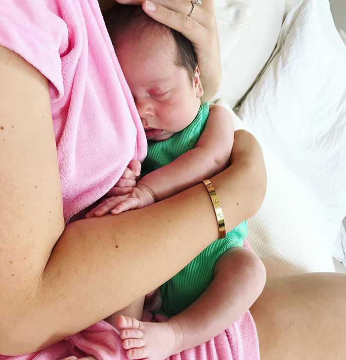 A person in a pink robe lovingly cradling a sleeping baby wearing green. A person in a pink robe lovingly cradling a sleeping baby wearing green.