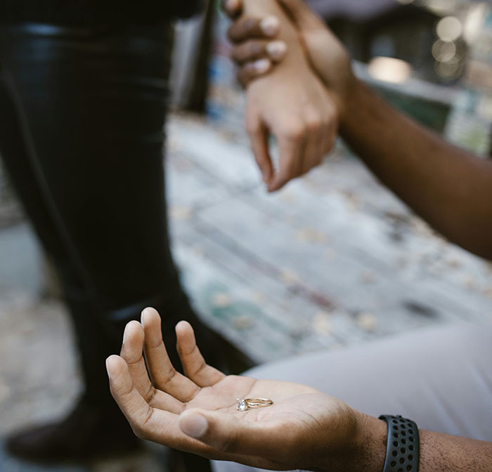 Man holding ring, woman's hand held; represents marriage influencer scam. Man holding ring, woman's hand held; represents marriage influencer scam.