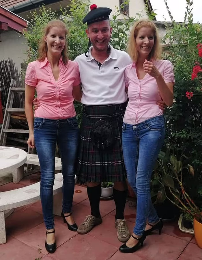 Two women in matching pink shirts and jeans with a man in a kilt, smiling outdoors. Two women in matching pink shirts and jeans with a man in a kilt, smiling outdoors.