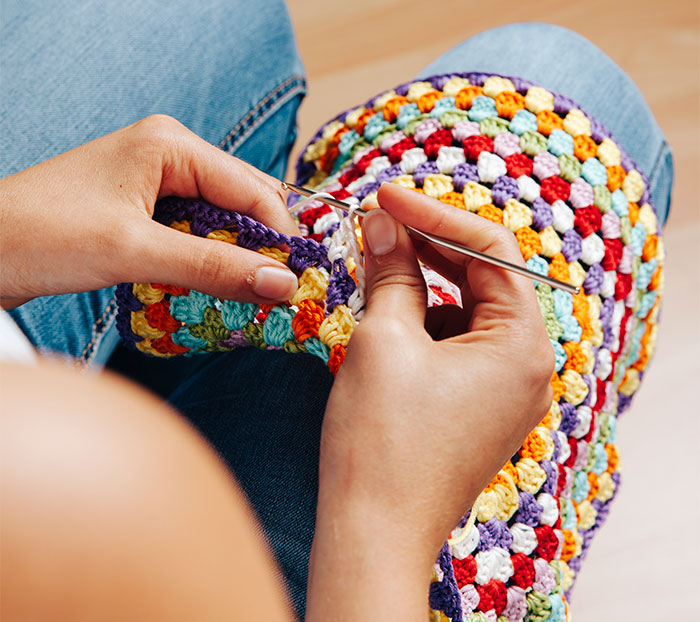 Person crocheting a colorful handmade gift with a crochet hook, focusing on intricate details. Person crocheting a colorful handmade gift with a crochet hook, focusing on intricate details.