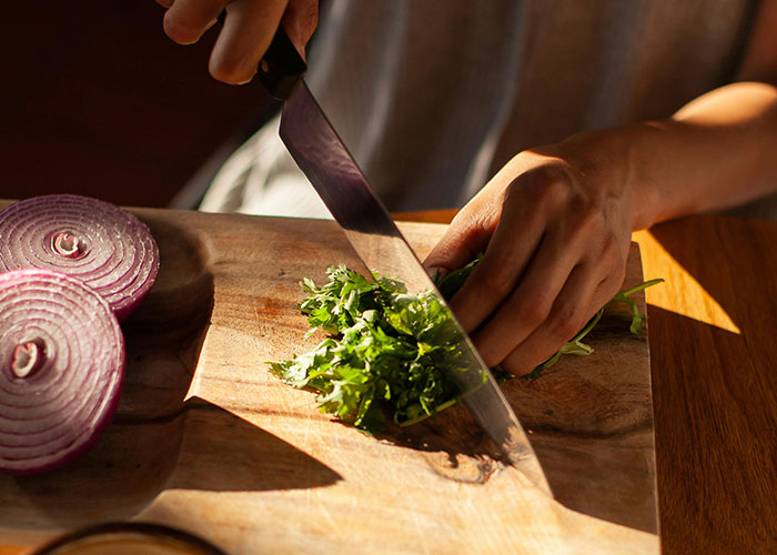 Person chopping vegetables on a wooden board, highlighting a vegetarian meal preparation. Person chopping vegetables on a wooden board, highlighting a vegetarian meal preparation.