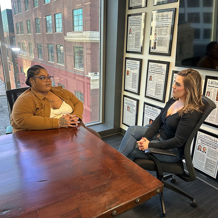 Plus size woman consulting with a lawyer at an office desk, framed articles on the wall in the background. Plus size woman consulting with a lawyer at an office desk, framed articles on the wall in the background.