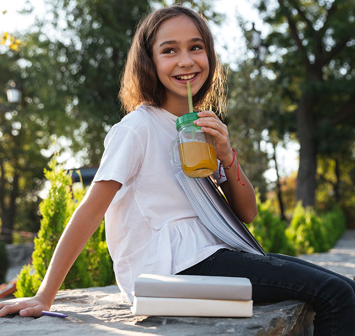 Young girl smiling while drinking a milkshake outdoors. Young girl smiling while drinking a milkshake outdoors.