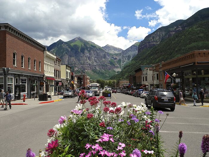 Main street with flowers and cars, framed by mountains in one of the amazing-views states.